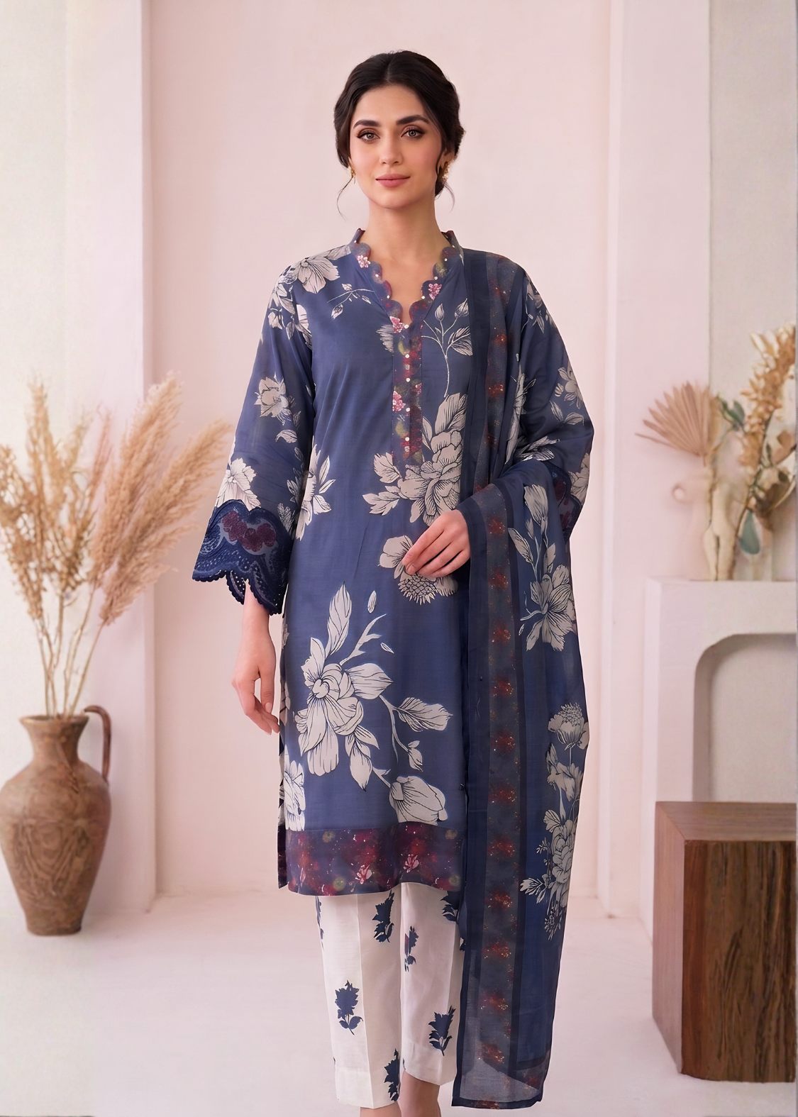 Woman wearing a blue floral dress with white pants in a minimalistic setting.