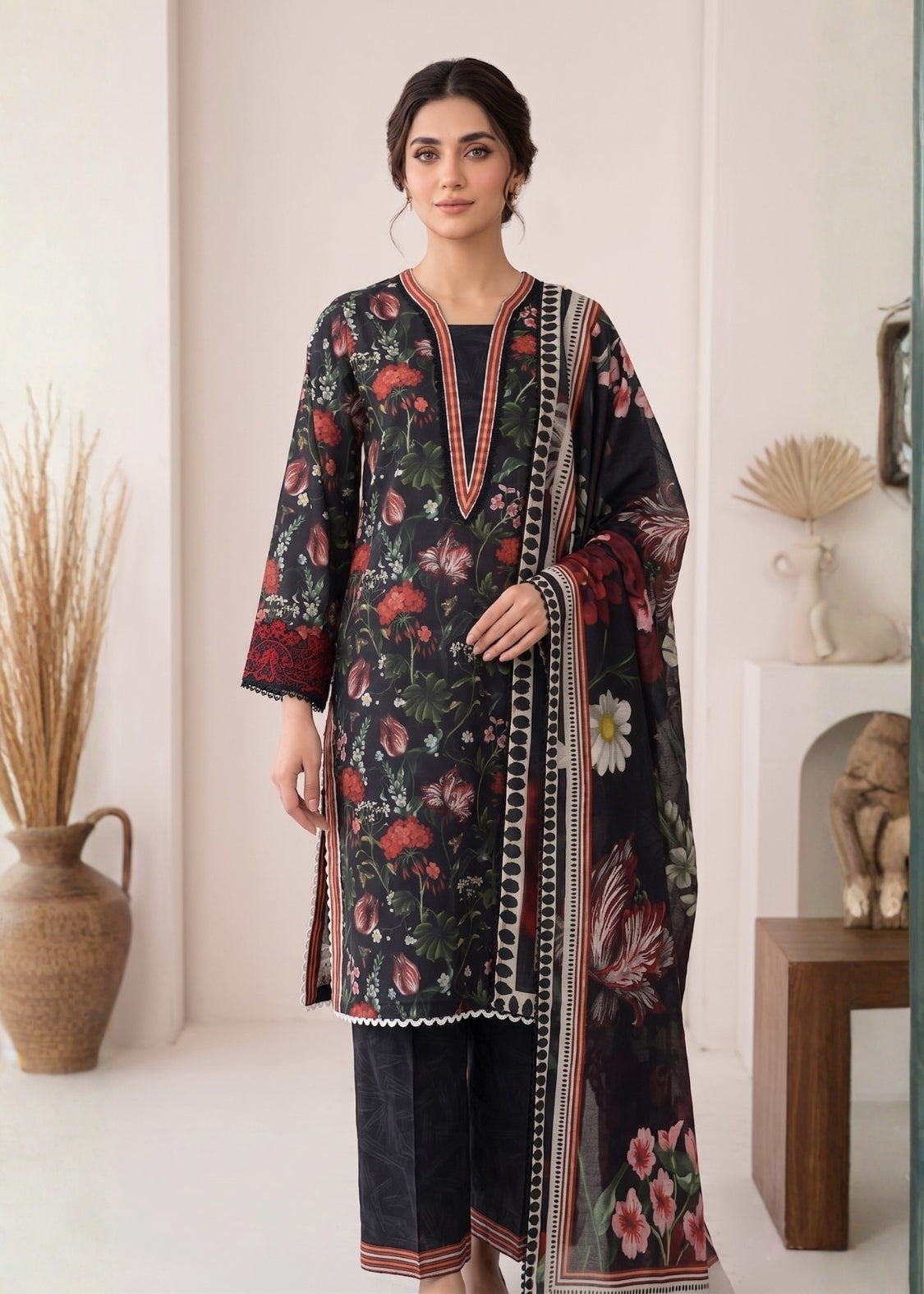 Woman wearing a floral dress with a matching dupatta in a minimalistic room.