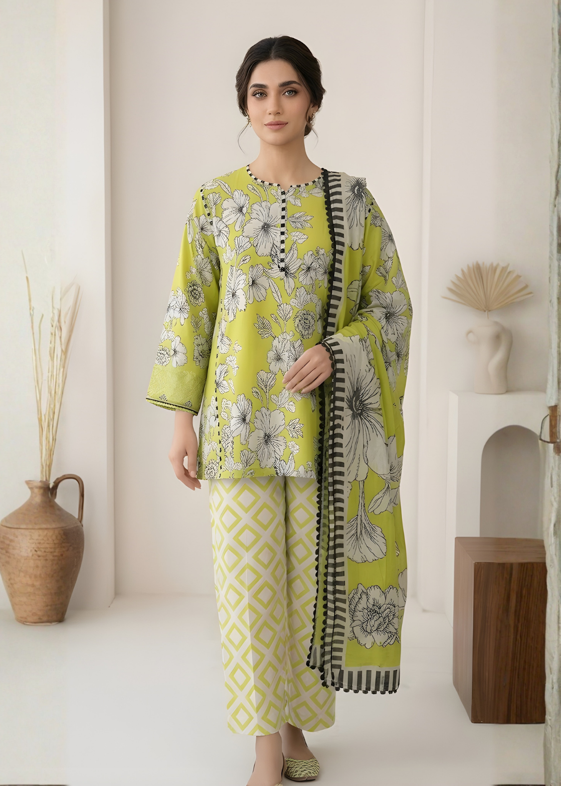 Woman wearing a green and white floral outfit with a matching scarf in a minimalistic setting.