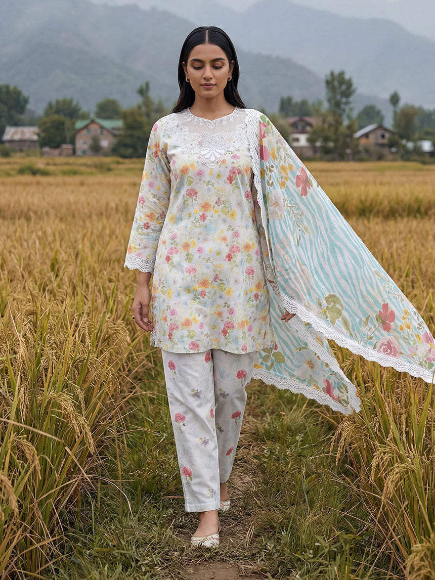Woman in a floral outfit standing in a field with mountains in the background